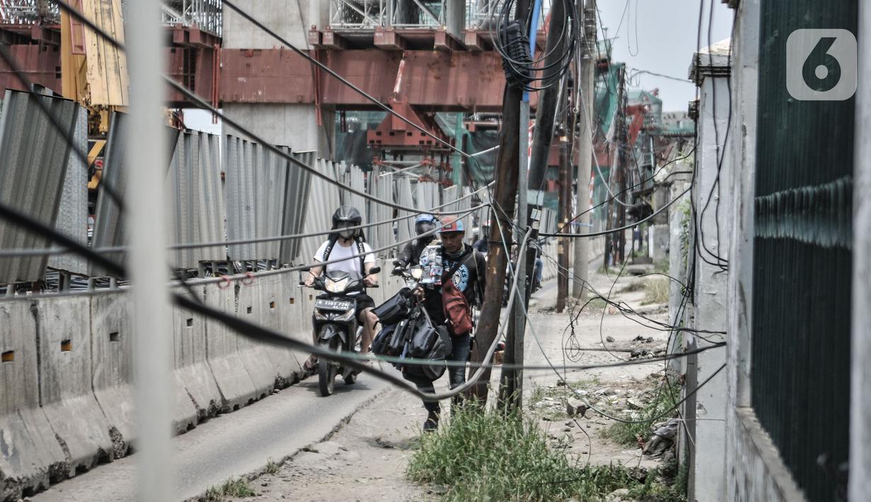 Pemotor melintas dekat instalasi kabel yang semrawut di Jalan Raya Bekasi, Cakung, Jakarta, Rabu (30/9/2020). Minimnya perawatan pascapembebasan lahan permukiman untuk proyek Tol Dalam Kota membuat jaringan kabel listrik di sepanjang jalan tersebut semrawut. (merdeka.com/Iqbal S. Nugroho)