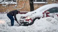 Seorang pria menggali untuk memindahkan mobilnya usai dilanda badai salju di Moskow (5/2). Suhu udara di sana mencapai minus 34 derajat celcius. (AFP/Vasily Maximov)