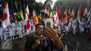 Warga berselfie saat melihat arak-arakan bendera di kawasan Bundaran HI, Jakarta, Minggu (30/10). Parade ini merupakan rangkaian arak-arakan parade Bendera Menjelang Sidang Umum Interpol Ke-85. (Liputan6.com/Johan Tallo)