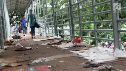 Sampah berserakan di koridor Jembatan Penyebrangan Orang (JPO) Jalan Medan Merdeka Barat, Jakarta, Selasa (1/1). Pasca malam perayaan pergantian tahun JPO Medan Merdeka Barat masih tampak kotor. (Liputan6.com/Helmi Fithriansyah)