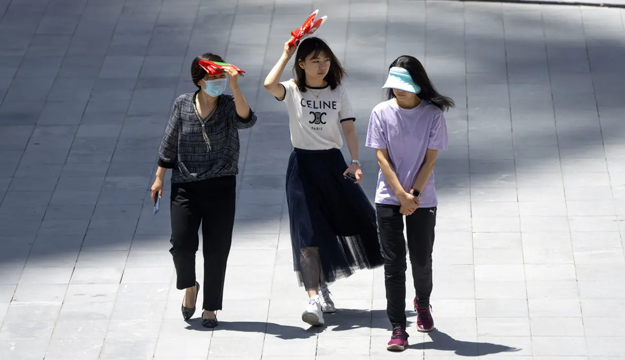 <p>Para wanita melindungi diri dari sinar matahari saat mereka berjalan melintasi alun-alun di kompleks perbelanjaan dan perkantoran pada hari yang panas di luar musimnya di Beijing, China, Rabu (7/6/2023). Suhu tinggi di Ibu Kota China itu diperkirakan sekitar 100 derajat Fahrenheit (38 derajat Celcius) pada hari Selasa. (AP Photo/Mark Schiefelbein)</p>