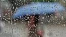 Seorang wanita memakai payung di balik jendela stasiun trem saat hujan deras di Erfurt, Jerman, (29/6). Curah hujan yang tinggi yang mengakibatkan banjir telah menimbulkan kekacauan dalam transportasi di dalam kota. (AP Photo / Jens Meyer)