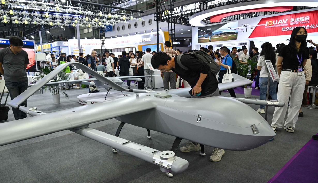 Seorang pria melihat model drone VTOL sayap tetap M12 di stan Micro Multi Copter (MMC) selama Drone World Congress (DWC) di Shenzhen pada 21 Mei 2026. (HECTOR RETAMAL/AFP)
