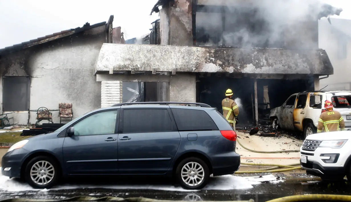 Petugas pemadam kebakaran menyemprotkan air di lokasi kecelakaan pesawat di sebuah rumah di Yorba Linda, California (3/2). Hingga kini penyebab kecelakaan masih diselidiki. (AP Photo/Alex Gallardo)