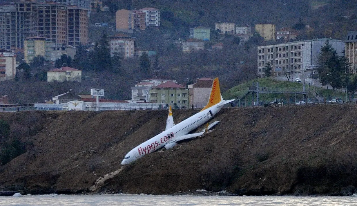 Pesawat maskapai Pegasus Airlines nyaris terperosok ke dalam laut saat mendarat di bandara Trabzon, Turki, Minggu (14/1). Pesawat itu tergeletak di tebing dengan bagian depannya hanya beberapa meter dari permukaan air Laut Hitam. (DHA-Depo Photos via AP)