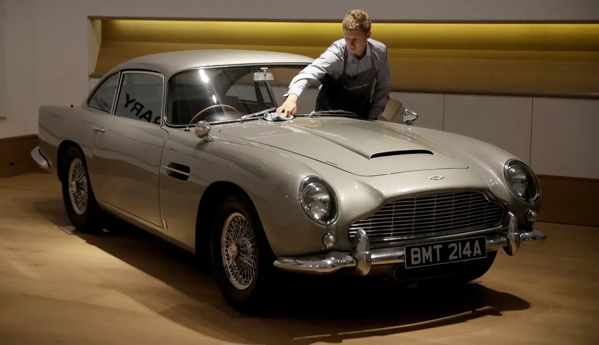 Seorang staf berpose dengan Aston Martin DB5 yang digunakan dalam film James Bond GoldenEye tahun 1995 di rumah lelang Bonham, London, Selasa (19/6). Mobil legendaris yang dikemudikan aktor Pierce Brosnan itu bakal dilelang pemiliknya. (AP/Matt Dunham)