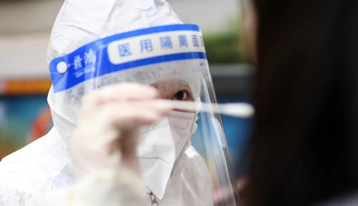 Petugas medis mengambil sampel swab dari seorang warga untuk tes virus corona Covid-19 di Wuhan, Provinsi Hubei, China tengah,  Selasa (22/2/2022). Wuhan, wabah besar pertama dari pandemi virus corona melaporkan lebih dari selusin kasus virus corona baru minggu ini. (AFP/China Out)
