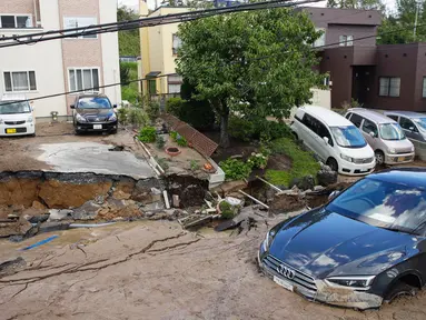 Sebuah mobil terjebak di jalan yang rusak akibat gempa mengguncang Sapporo di prefektur Hokkaido, pada Kamis (6/9). Gempa magnitudo 6,7 yang mengguncang Hokkaido kemudian memicu tanah longsor. (Hiroki Yamauchi/Kyodo News via AP)