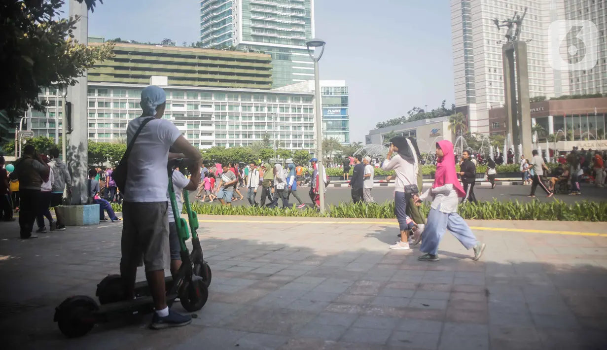 Warga membawa skuter listrik saat Car Free Day (CFD) di kawasan Bundaran HI, Jakarta, Minggu (17/11/2019).  Skuter listrik dilarang digunakan saat CFD karena dianggap masih menggunakan motor sehingga tak bisa disesuaikan dengan sepeda. (Liputan6.com/Faizal Fanani)
