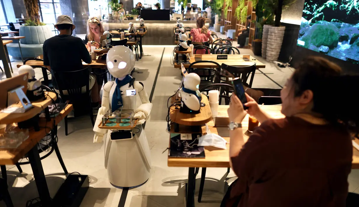 Robot humanoid mengantarkan minuman kepada pelanggan di Dawn Cafe, Tokyo, Jepang, 17 Agustus 2021. Peluncuran kafe ini bersamaan dengan Paralimpiade yang akan dibuka pada 24 Agustus. (Behrouz MEHRI/AFP)