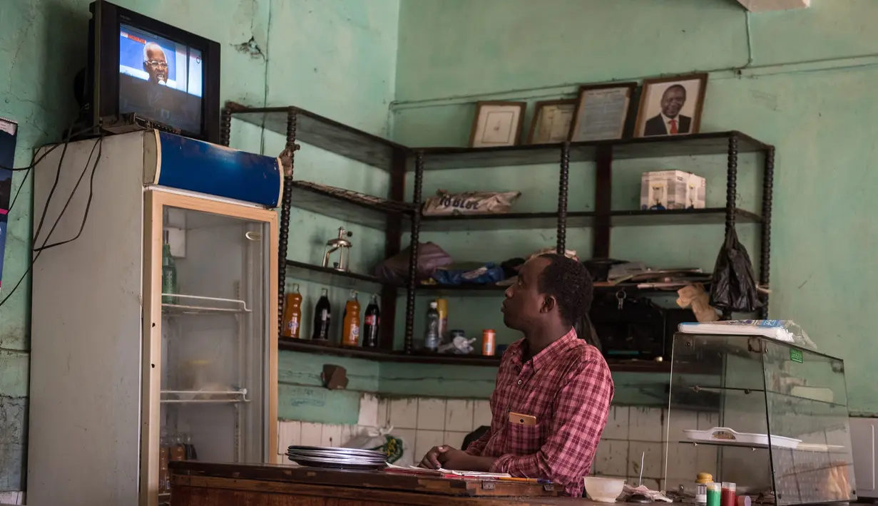 Penjaga menonton televisi sebuah konferensi pers dari Pejabat Uni Afrika di sebuah restoran sambil menunggu hasil resmi pemilihan umum Kenya di Kisumu (10/8). Berdasar laporan, Uhuru Kenyatta masih unggul dari Raila Odinga. (AFP Photo/Jennifer Huxta)