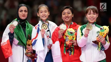 Karateka putri Indonesia, Cokorda Istri Agung Sanistyarani (kedua kanan) menunjukkan medali perunggu usai memenangkan pertandingan di babak final nomor Kumite 55 kg di Arena Karate JCC Senayan, Jakarta, Minggu (26/8). (Liputan6.com/Fery Pradolo)