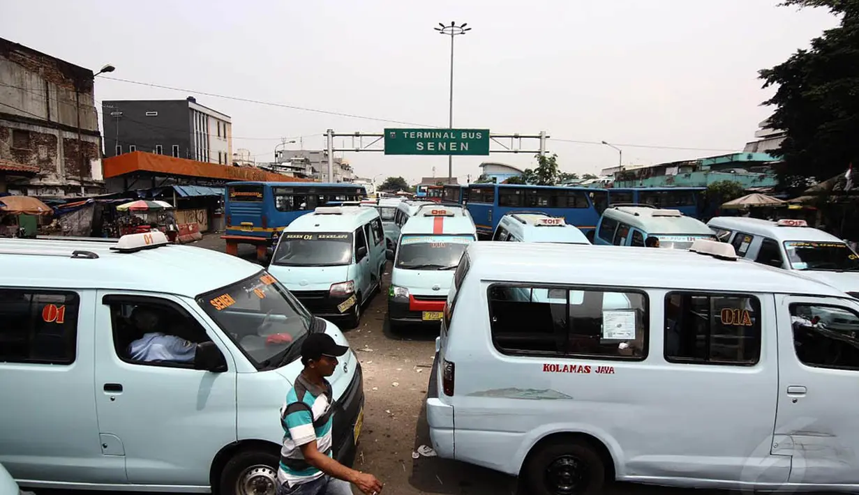 Warga melintasi angkutan umum yang sedang parkir di Terminal Senen, Jakarta, Senin (24/11/2014). (Liputan6.com/Faizal Fanani)