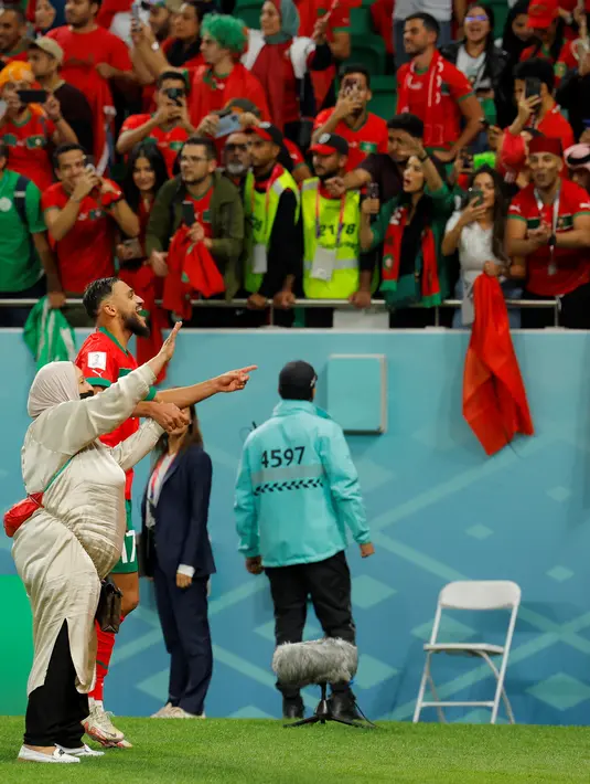 Gelandang Maroko #17 Sofiane Boufal merayakan bersama ibunya setelah lolos ke semifinal dengan mengalahkan Portugal pada babak 8 besar Piala Dunia 2022 di Stadion Al-Thumama di Doha, Sabtu (10/12/2022). Sofiane Boufal menghampiri ibunya yang berada di tepi lapangan. (Photo by Odd ANDERSEN / AFP)