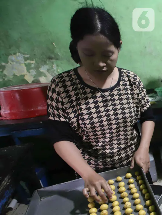 Pekerja menyelesaikan pembuatan kue kering skala rumah tangga Pusaka Kwitang di kawasan Senen, Jakarta, Rabu (13/4/2022). Pedagang mengaku terpaksa menaikkan harga jual kue kering Ramadhan akibat tingginya harga bahan baku. (Liputan6.com/Herman Zakharia)