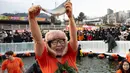 Penyelenggara memperkirakan festival ini akan menarik lebih dari satu juta pengunjung tahun ini, termasuk target 100.000 wisatawan mancanegara. Tampak dalam foto, seorang wanita bereaksi saat menangkap ikan trout dengan tangan selama festival tahunan memancing di atas es, Hwacheon, Korea Selatan, pada Sabtu 10 Januari 2026. (Shin Yong-ju/AFP)