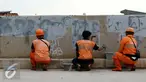 Petugas Pekerja Penanganan Sarana dan Prasarana Umum (PPSU) mengecat tembok yang penuh dengan vandalisme di sepanjang sisi tanggul Kali Ciliwung, Jakarta, Selasa (11/10). (Liputan6.com/Gempur M Surya)