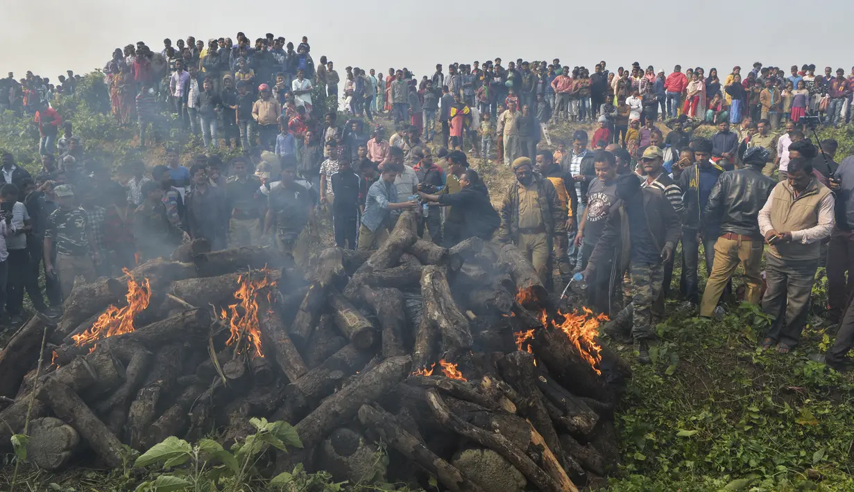 Polisi dan pekerja kehutanan bersama penduduk desa menyaksikan tubuh gajah dibakar setelah kereta penumpang melaju menabrak dua gajah yang melintasi rel di desa Batasi dekat perbatasan India-Nepal, sekitar 37 km dari Siliguri (11/12/2019). (AFP/Diptendu Dutta)