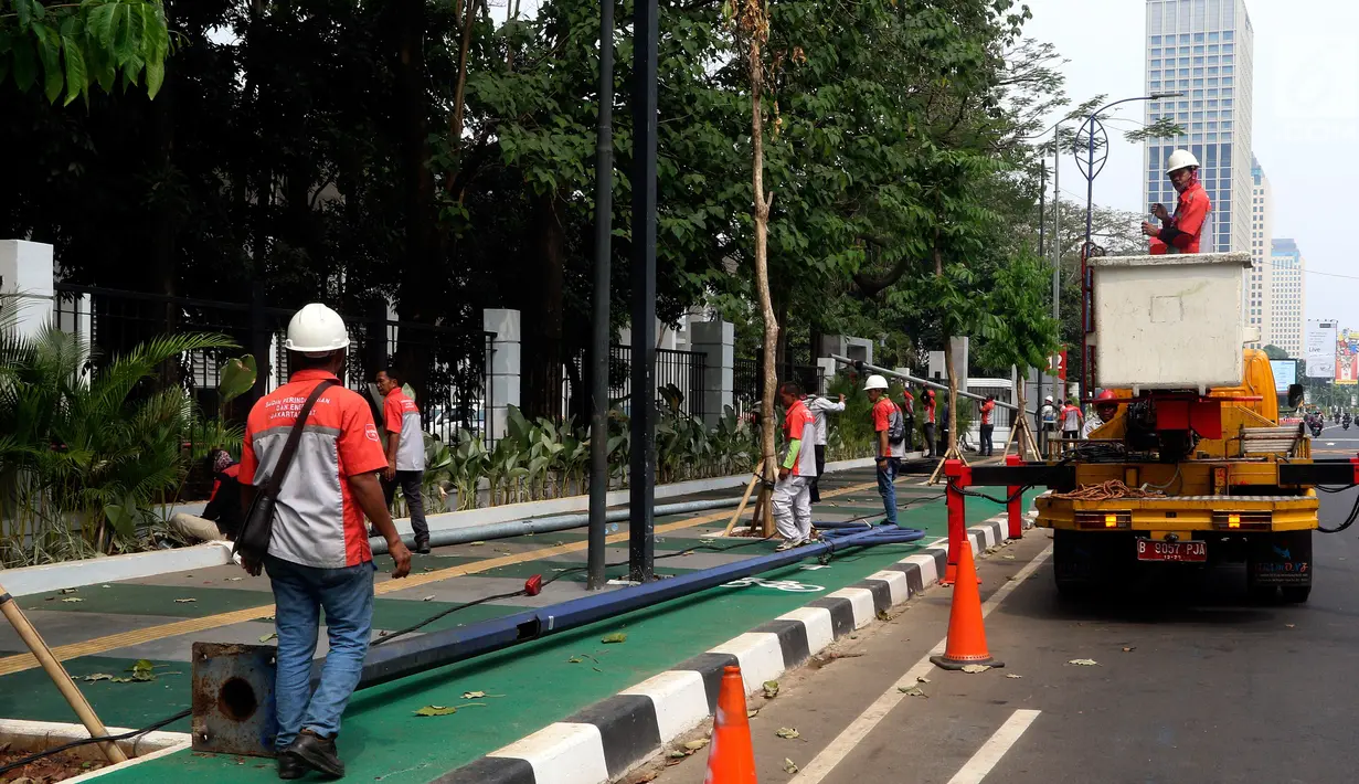 Petugas Suku Dinas PE Jakarta Pusat bersama Satgas PJU, mencabut dan menggeser tiang listrik dan lampu penerangan jalan yang menghalangi jalur sepeda di trotoar Jalan Asia Afrika dan Jalan Gelora, Senayan, Jakarta, Rabu (1/8). (Liputan6.com/Johan Tallo)