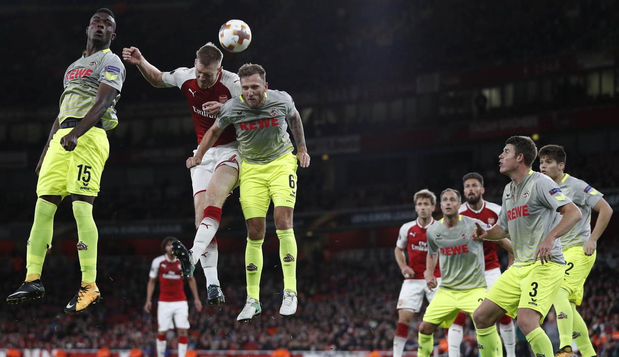 Bek Arsenal, Per Mertesacker, duel udara dengan striker FC Cologne, Jhon Andres Cordoba, pada laga Liga Europa di Stadion Emirates, London, Rabu (14/9/2017). Arsenal menang 3-1 atas Cologne. (AFP/Adrian Dennis)