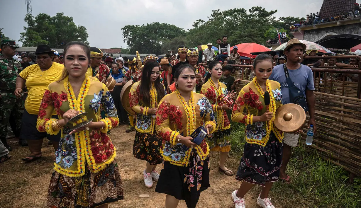 Orang-orang memainkan alat musik saat mereka mengambil banteng untuk parade selama kompetisi balap banteng Karapan Sapi di Bangkalan, pulau Madura, Jawa Timur, Minggu (16/10/2022). Lomba karapan sapi yang memperebutkan Piala Presiden itu diikuti 24 pasang sapi dari sejumlah daerah di Madura. (Juni Kriswanto/AFP)