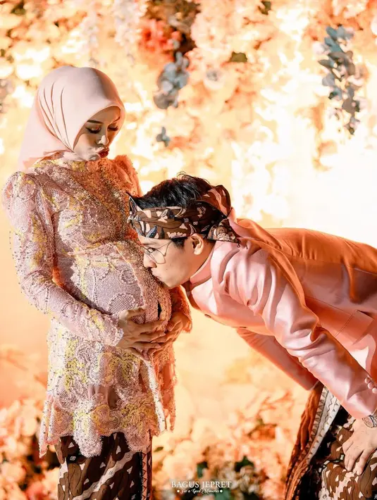 Saat 7 bulanan, Lesti Kejora kenakanp perpaduan kebaya Kartini dan kutubaru warna peach. Memiliki detail lace berwarna kuning, kebaya ini dipadukan dengan kain Batik warna gelap dan hijab polos [@lestikejora]