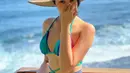 Ketika hendak berenang, Anya mengenakan bikini warna biru yang ditutupi dengan kain pantai abu-abunya. Serta dipermanis dengan topi jerami. @anyageraldine.