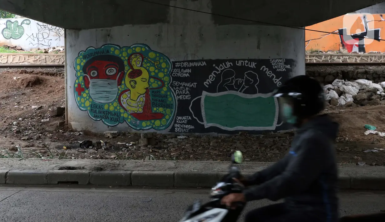 Pengendara motor melintas di dekat mural bertema pencegahaan penyebaran virus Corona atau COVID-19 di Jakarta, Selasa (7/4/2020). Mural tersebut menghimbau masyarakat untuk menjaga jarak fisik dan selalu menggunakan masker serta tetap beraktivitas di dalam rumah. (Liputan6.com/Helmi Fithriansyah)