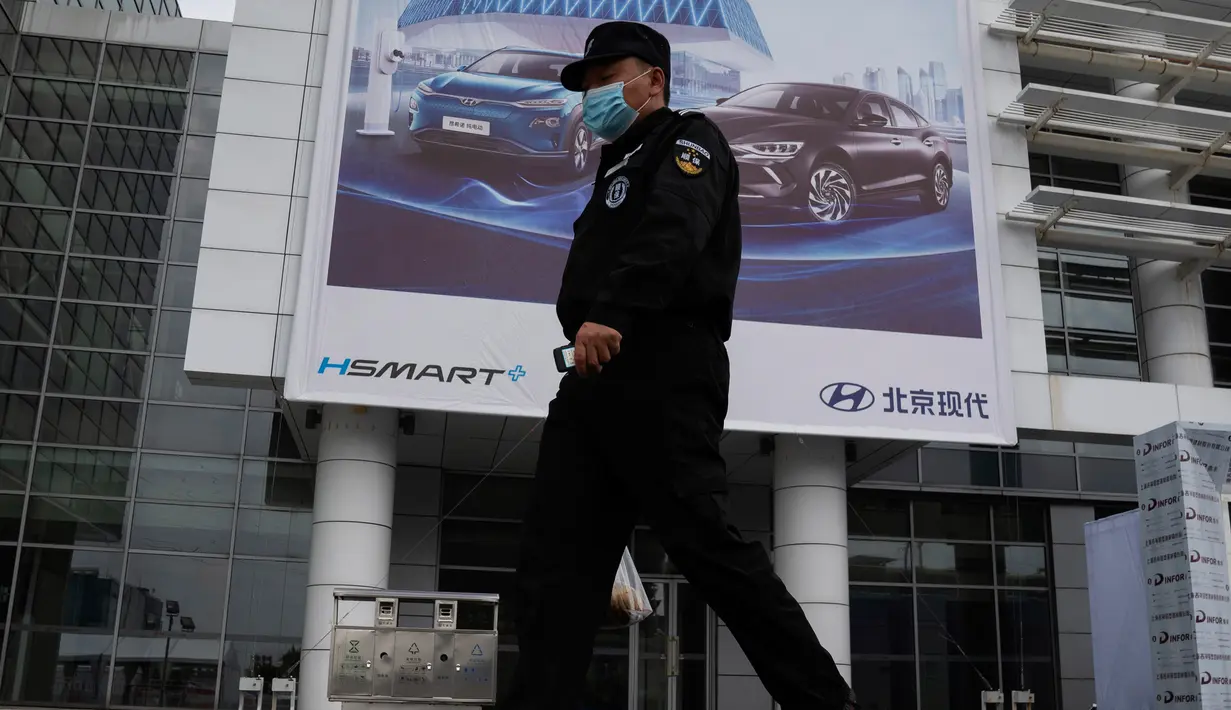 Seorang petugas keamanan berjalan melewati iklan untuk pameran Auto China 2020 yang akan digelar di Beijing, Kamis (24/9/2020). Menandai bangkitnya kembali industri otomotif negara dengan penduduk terbanyak di dunia ini, China mengumumkan siap menggelar Auto China 2020. (AP Photo/Ng Han Guan)
