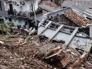 Warga membersihkan puing reruntuhan bangunan pascatanah longsor di kawasan Kemang Timur XI, Jakarta Selatan, Minggu (21/2/2021). Tanah longsor yang berasal dari bangunan rumah elite tersebut terjadi pada Sabtu (20/2) dini hari. (merdeka.com/Iqbal S. Nugroho)
