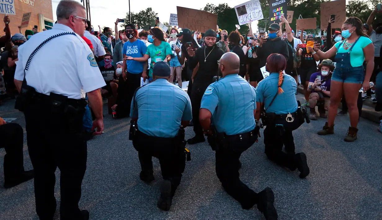 Petugas polisi dari Ferguson bergabung dengan pengunjuk rasa untuk mengenang George Floyd dengan berlutut di tempat parkir kantor polisi  Missouri pada 30 Mei 2020. George Floyd, tewas tak bisa bernafas karena tercekik lutut polisi saat ditangkap pada (25/5/2020) lalu . (Robert Cohen/St. Louis Post-