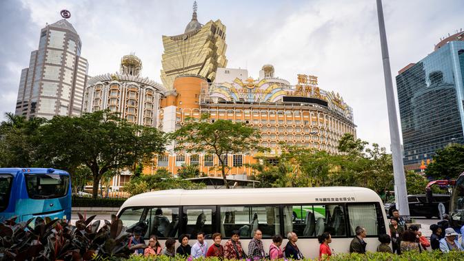 Wisatawan antre untuk menaiki bus dengan latar belakang resor kasino Grand Lisboa (tengah) di Macau, 5 Maret 2019. Hampir setengah PDB Macau atau sekitar 45 miliar dolar AS bersumber dari perjudian. (Anthony Wallace/AFP)