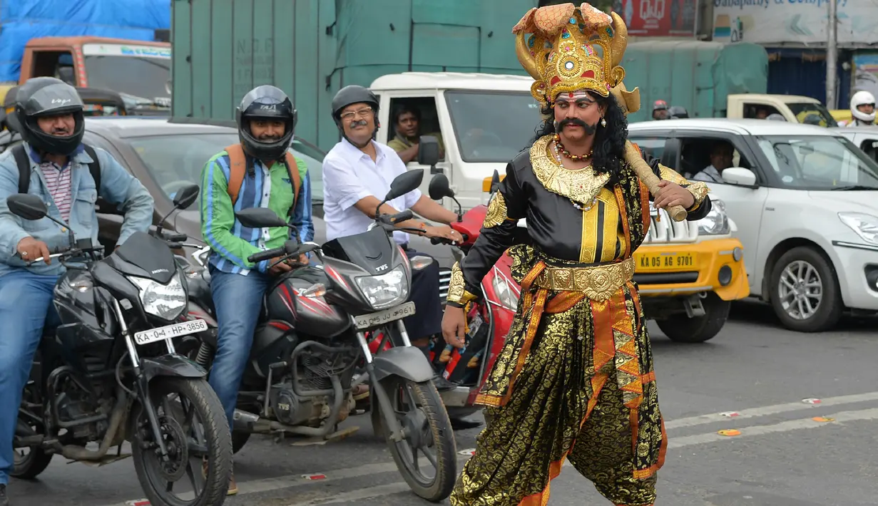 Seniman berpakaian seperti "Yamaraj" (R), dewa kematian Hindu mengatur lalu lintas di Bangalore (10/7). Kampanye ini bertujuan untuk membawa kesadaran pengendara tentang pentingnya peraturan keselamatan lalu lintas. (AFP Photo/Manjunath Kiran)