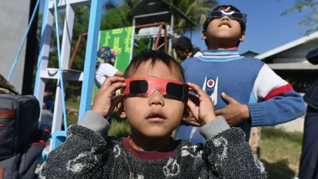 Anak-anak di Wan Twin, Myanmar menggunakan kacamata khusus untuk menyaksikan gerhana matahari cincin.