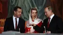 Presiden Rusia Vladimir Putin (kanan) bersama Perdana Menteri Rusia Dmitry Medvedev (kiri) dan istrinya Svetlana saat menjalani prosesi Paskah Ortodoks di Gereja Katedral Kristus Juru Selamat di Moskow, Rusia,(16/4). (AFP Photo / Vasily Maximov)