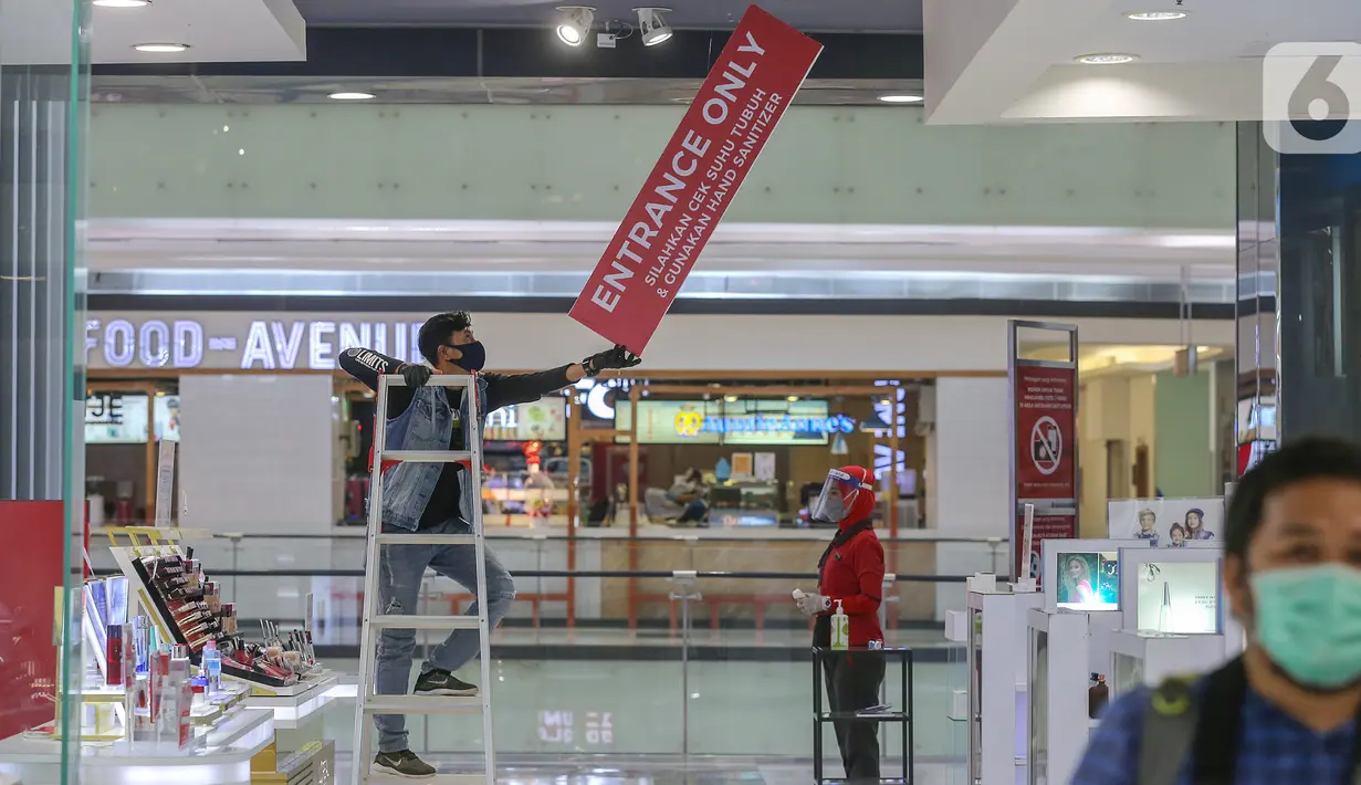Pekerja memasang papan himbauan protokol kesehatan di salah satu tenant di Lippo Mall Puri, Jakarta, Senin (15/6/2020). Lippo Malls di wilayah Jakarta kembali beroperasi pada pukul 12.00 – 20.00 WIB dengan menyiapkan protokol kesehatan guna mencegah penyebaran Covid-19. (Liputan6.com/Fery Pradolo)