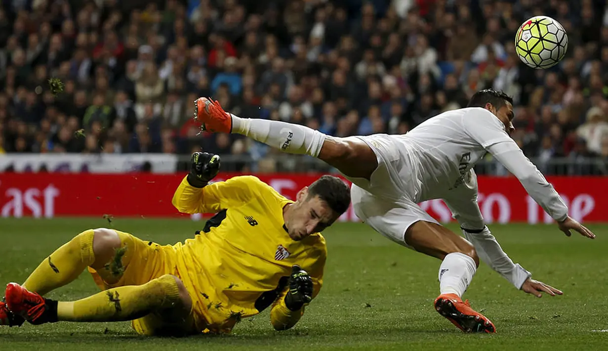 Pemain Real Madrid, Cristiano Ronaldo, berebut bola dengan kiper Sevilla, Sergio Rico, pada laga La Liga Spanyol di Stadion Santiago Bernabeu, Madrid, Minggu (20/3/2016). Gol Madrid dicetak oleh Benzema, Ronaldo, Bale dan Jese. (Reuters/Sergio Perez)