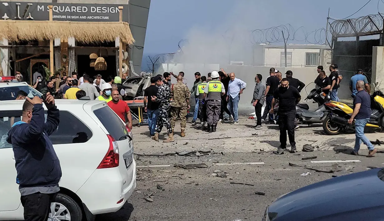 Petugas pertolongan pertama dan warga yang lewat berkumpul di sekitar reruntuhan kendaraan yang menjadi sasaran serangan pesawat tak berawak Israel di kota Jiyeh, Selatan Beirut, pada Rabu 13 Mei 2026. (Fadel ITANI/AFP)