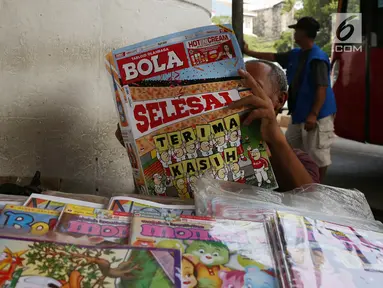 Pedagang membaca tabloid Bola di Terminal Kampung Melayu, Jakarta, Jumat (26/10). Hari ini menjadi terakhir tabloid Bola terbit. (Merdeka.com/Imam Buhori)