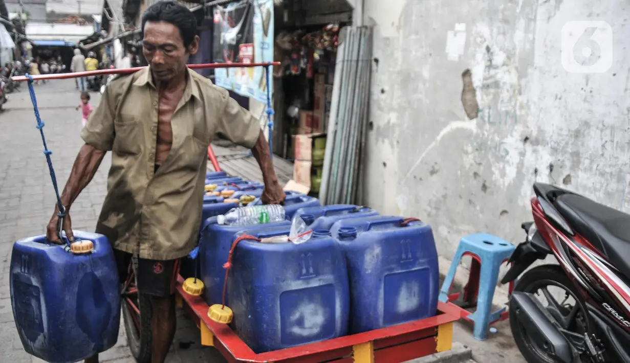 Pedagang mengantarkan air pikulan kepada warga di kampung nelayan Kalibaru, Cilincing, Jakarta Utara, Selasa (22/3/2022). Hingga kini air pikulan masih menjadi kebutuhan utama warga di kawasan pesisir Cilincing untuk keperluan konsumsi akibat air sumur keruh dan bau. (merdeka.com/Iqbal S Nugroho)