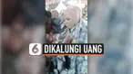 Satu per satu tamu undangan bergantian mengalungi uang pada pengantin pria dan wanita ini. Alhasil, pengantin ini dipenuhi dengan uang saat pesta pernikahannya.