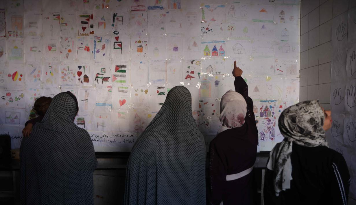 Pameran ini diselenggarakan untuk menyoroti dampak perang terhadap warga sipil, terutama anak-anak dan kaum perempuan. Tampak dalam foto, orang-orang melihat pameran yang menampilkan koleksi gambar oleh anak-anak dan perempuan di sebuah sekolah yang diubah menjadi tempat penampungan bagi pengungsi Palestina di kawasan Al-Rimal, Kota Gaza, pada 5 November 2025. (Omar AL-QATTAA/AFP)