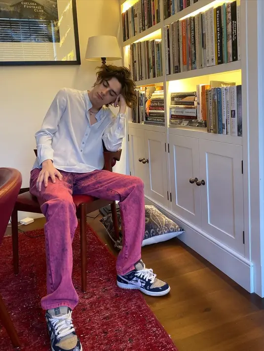 Dengan gaya semi formal, Timothee Chalamet kenakan kemeja putih dengan jeans berwarna dan sneakers.  [@tchalamet]
