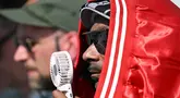 Rapper AS Snoop Dogg mengenakan jaket di kepalanya untuk melindungi dari panas dan memegang kipas portable untuk mendinginkan diri saat ia menonton final skateboard jalanan putra Olimpiade Paris 2024 di La Concorde, Senin (29/7/2024). (Kirill KUDRYAVTSEV / AFP)