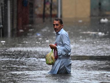 Seorang pria menyeberangi jalan yang tergenang air saat hujan monsun lebat di Rawalpindi, Pakistan, pada 17 Juli 2025. (Aamir Qureshi/AFP)