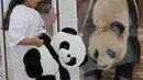 Seorang anak bermain dengan panda raksasa China dari balik kaca pelindung di Rumah Panda di Al Khor Park, dekat Doha, Qatar, Rabu (19/10/2022). Sebanyak 800 kilogram bambu segar akan diterbangkan setiap minggu untuk memberi makan sepasang panda yang berada di Qatar itu. (Photo by DENOUR / AFP)