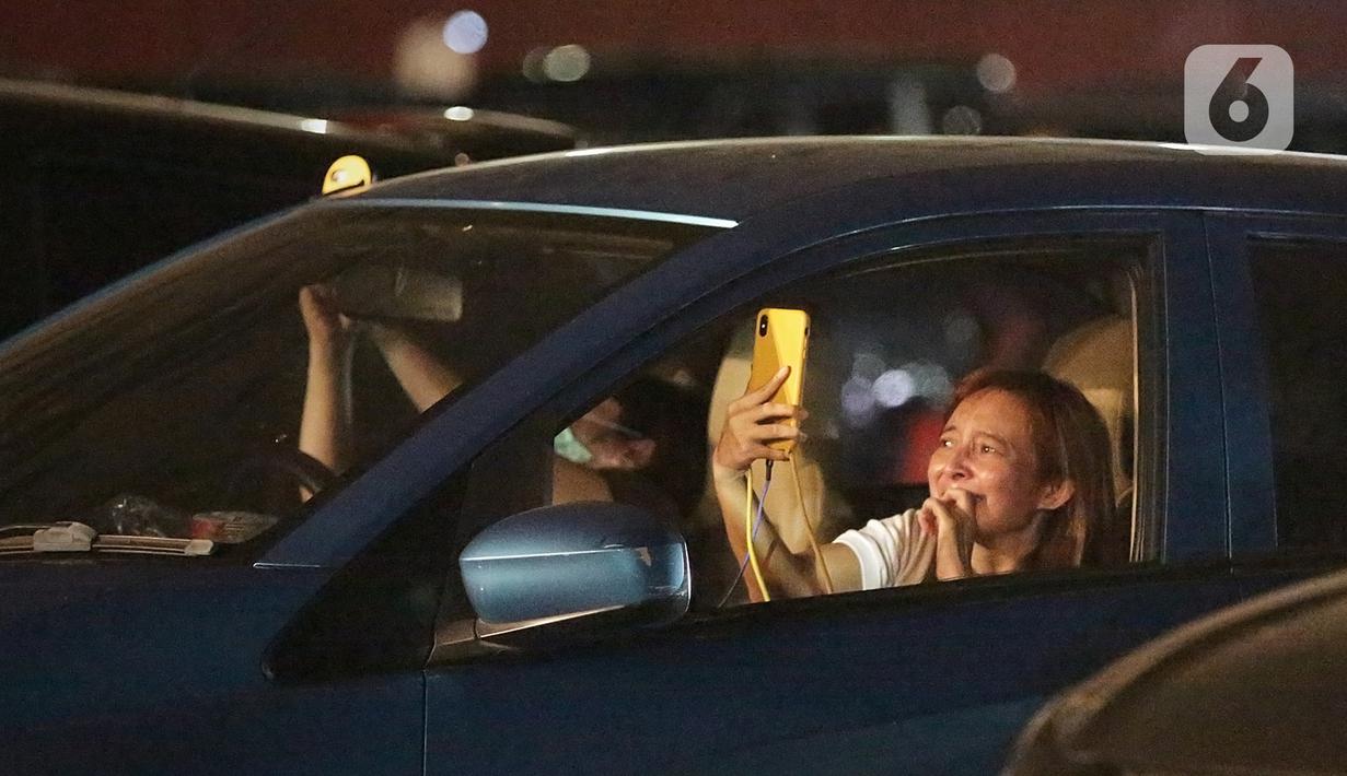 Seorang wanita mengabadikan penampilan Kahitna dalam konser New Live Experience 2020 di Parkir Barat JIExpo Kemayoran, Jakarta, Sabtu (29/8/2020). Pertunjukan diawali dengan lagu Padamu Negeri ini disambut para Soulmate, sebutan bagi penggemar Kahitna. (Fimela.com/Bambang E.Ros)