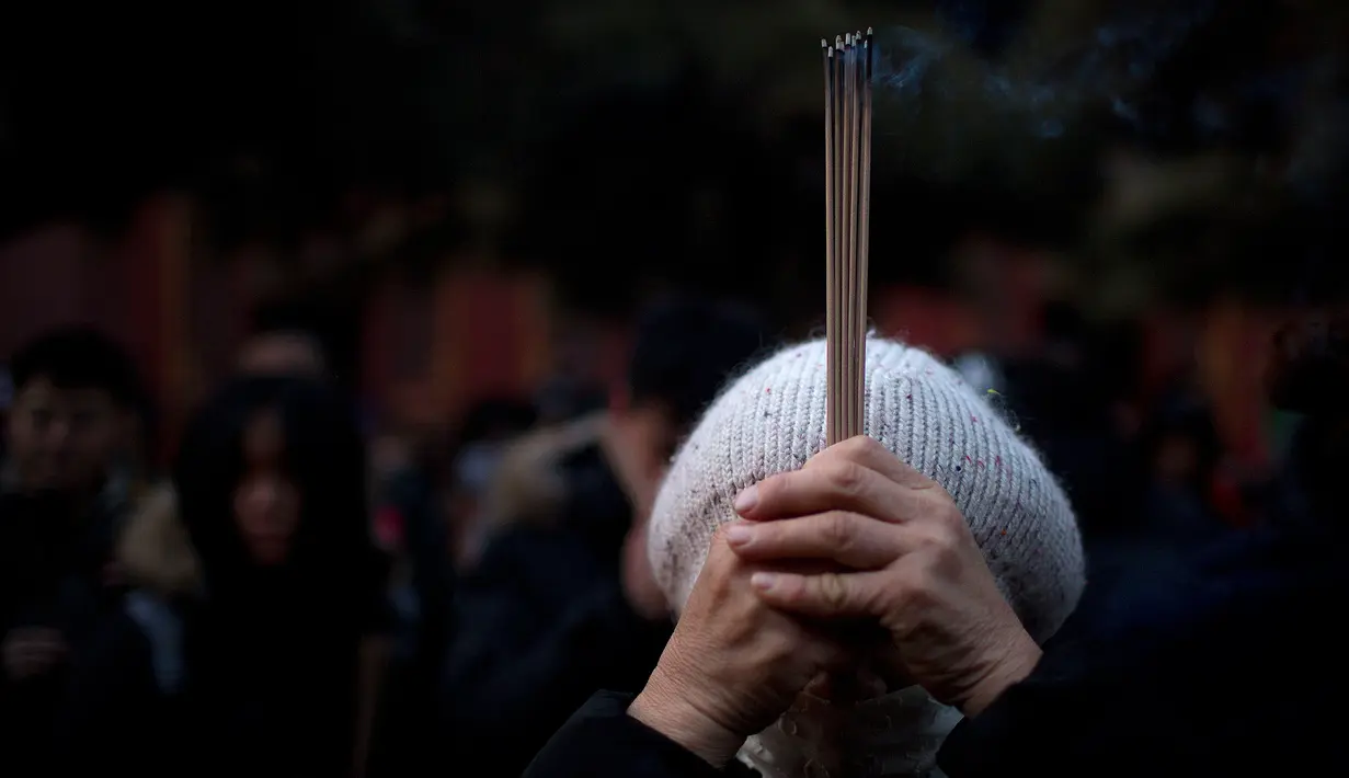 Seorang wanita memegang dupa berdoa di Kuil Lama di Beijing (5/2). Orang-orang China merayakan hari pertama Tahun Baru Imlek pada hari Selasa, Tahun Babi di zodiak Tiongkok dengan berdoa di kuil. (AP Photo/Mark Schiefelbein)