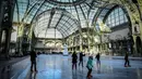 Orang-orang  berseluncur di arena ice skating di bawah kubah kaca mewah legendaris, Grand Palais, Paris, Senin (17/12). Tempat seluas 1.800 meter persegi ini menjadi arena ice skating sementara terbesar di Prancis. (STEPHANE DE SAKUTIN / AFP)