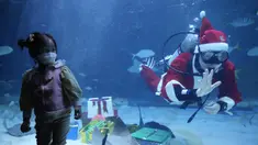 Seorang gadis melihat penyelam yang mengenakan pakaian Sinterklas pada acara untuk mempromosikan liburan Natal di Coex Aquarium, Seoul, Korea Selatan, Jumat (3/12/2021). Natal adalah salah satu hari libur terbesar yang dirayakan di Korea Selatan. (AP Photo/Ahn Young-joon)